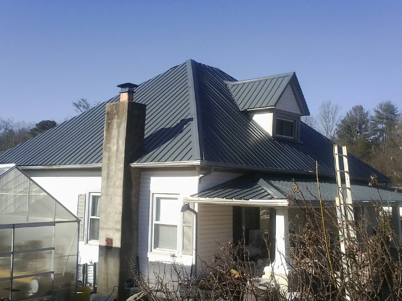 Dark blue standing seam metal roof on a white farmhouse with dormer — Slate & Tile Roof Repair by Roofing Brothers in Park Rapids