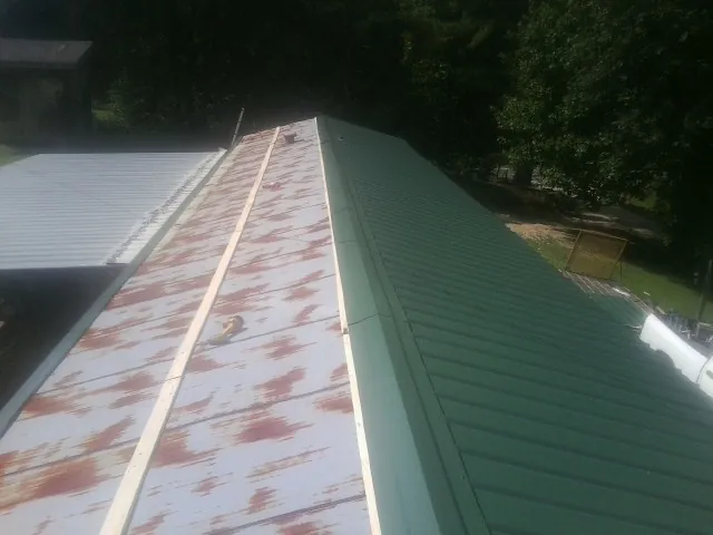 Old rusted panels beside newly installed green metal roofing — Wind Damage Roof Repair by Roofing Brothers in Park Rapids