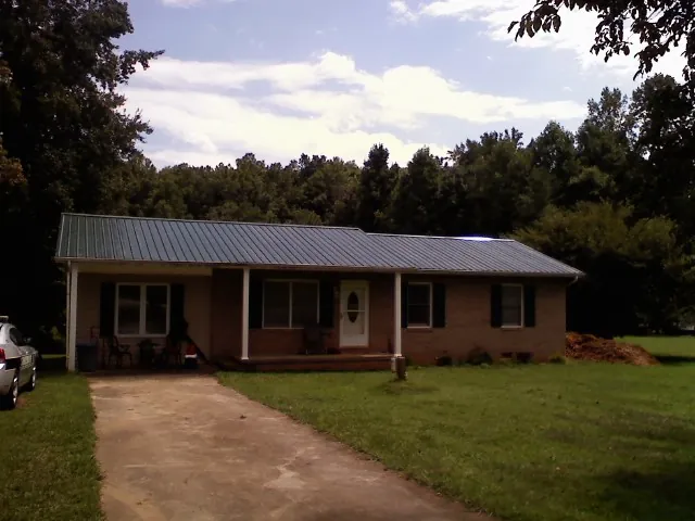 Dark green metal roof on a brick ranch with a covered porch in Park Rapids