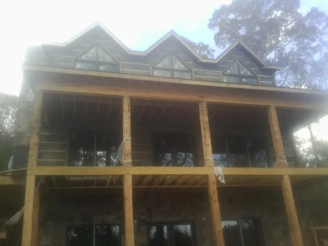 Dormers and porch framing on a large log home under construction — Roof Coating work by our crew in Park Rapids