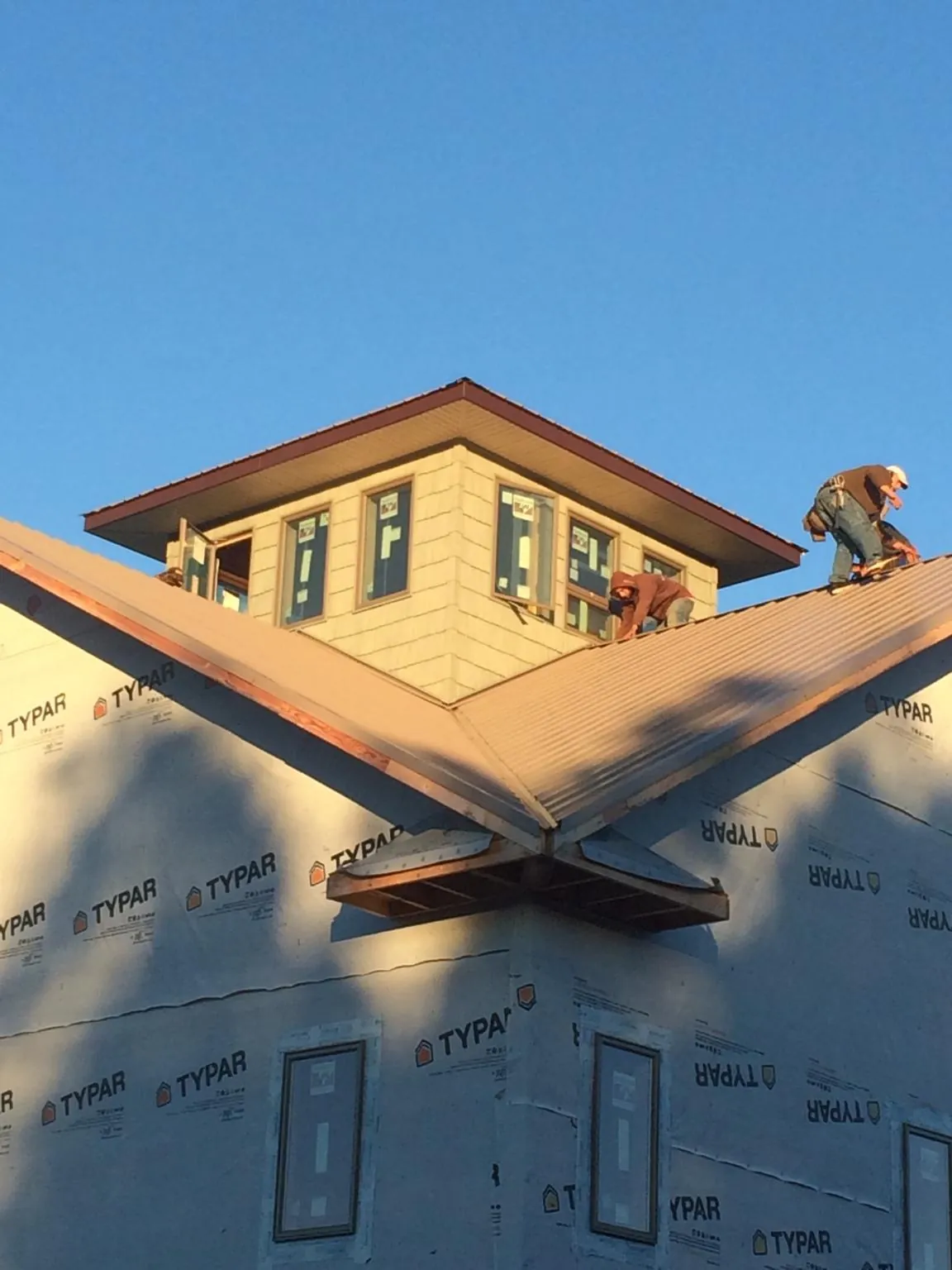 Roofers working around a rooftop cupola on a new metal roof at sunset — Roof Waterproofing in Park Rapids by Roofing Brothers